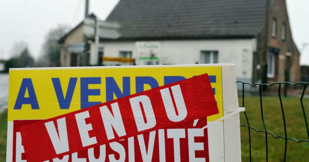 Un panneau d'agence immobilière devant une maison, dans le nord de la France