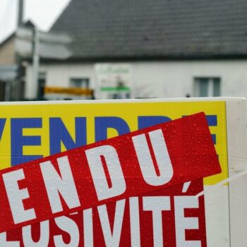 Un panneau d'agence immobilière devant une maison, dans le nord de la France