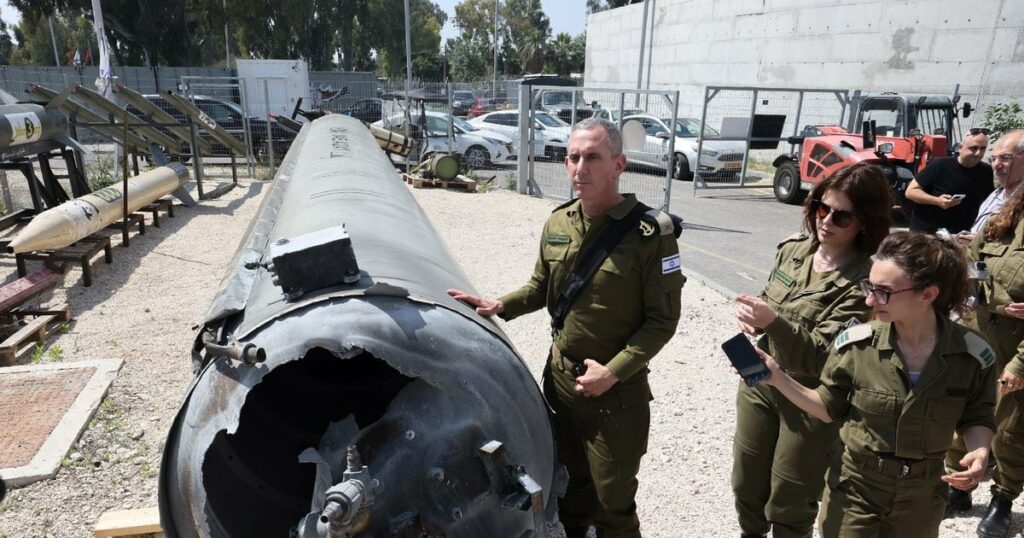 Le porte-parole de l'armée israélienne, le contre-amiral Daniel Hagari (C), et d'autres militaires se tiennent à côté d'un missile balistique iranien tombé en Israël, lors d'une tournée à la base de Julis dans le sud d'Israël, le 16 avril 2024