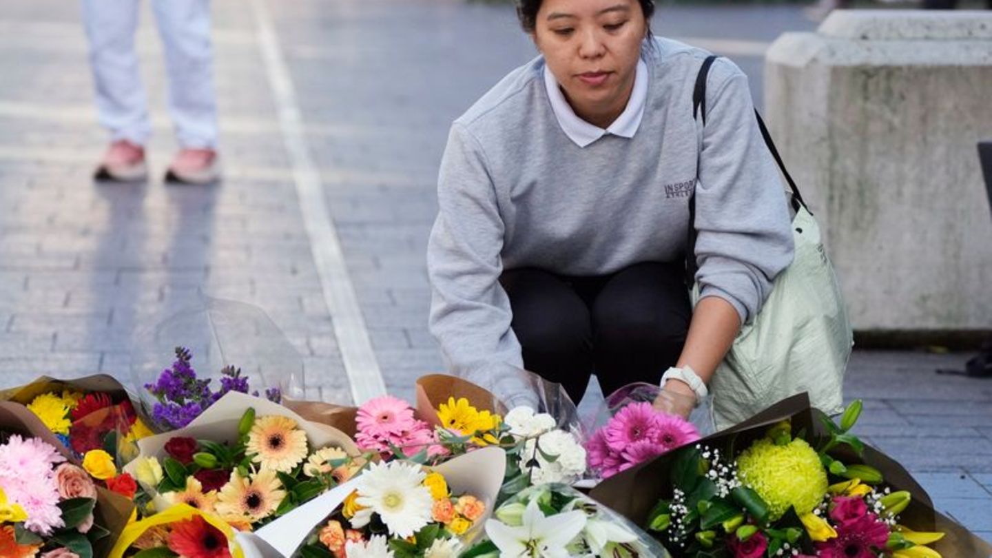 Eine Frau bringt Blumen zu einer improvisierten Gedenkstätte an der Bondi Junction. Foto: Rick Rycroft/AP/dpa