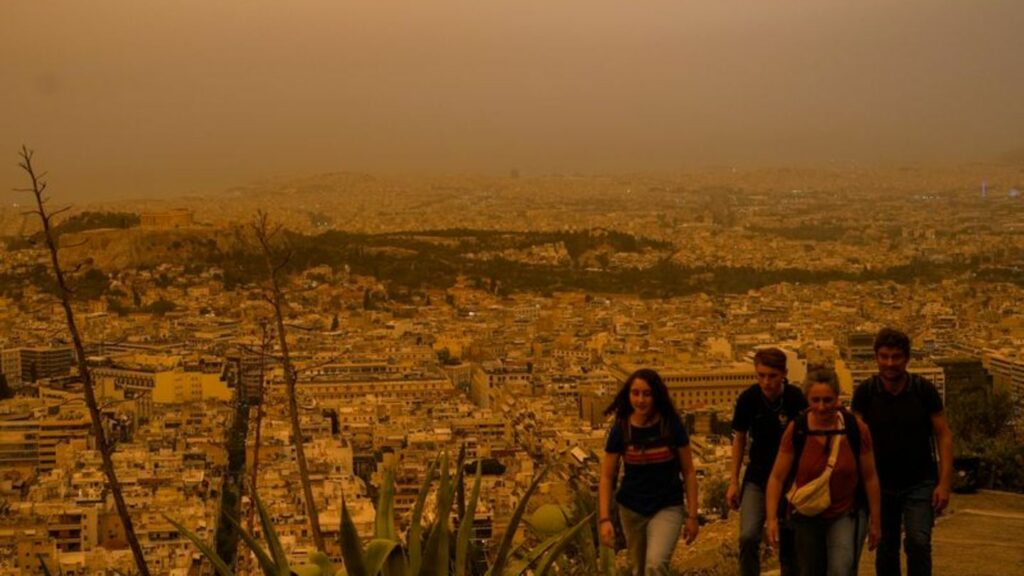 Touristen spazieren auf dem Lycabettus-Hügel, während der Himmel über Athen mit dem antiken Akropolis-Hügel im Hintergrund infol