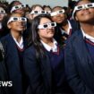 School children look at a solar eclipse through dark glasses