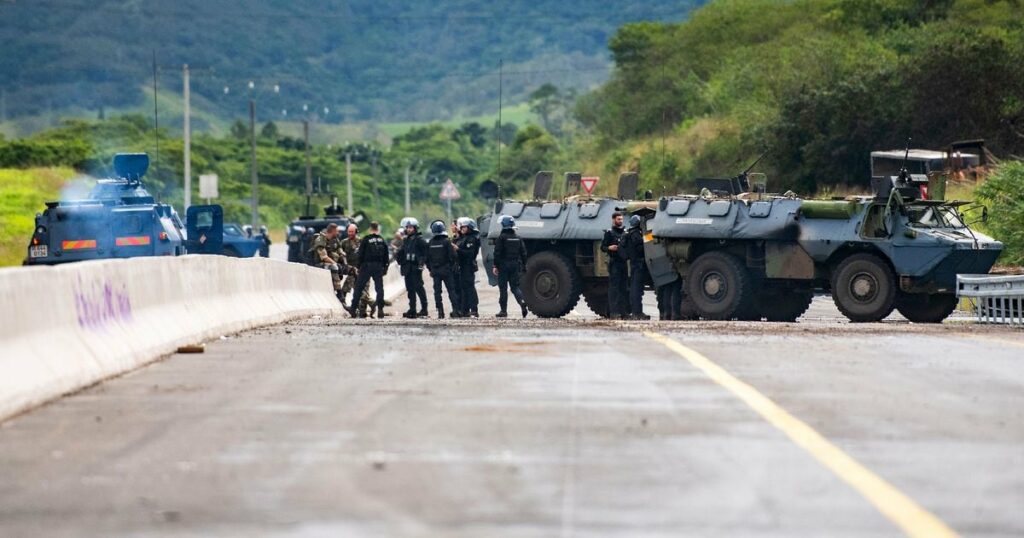 Des gendarmes mobiles sécurisent la zone pendant une opération de nettoyage de la route menant à l'aéroport de Nouméa dans le quartier de Païta, en Nouvelle-Calédonie, le 19 mai 2024