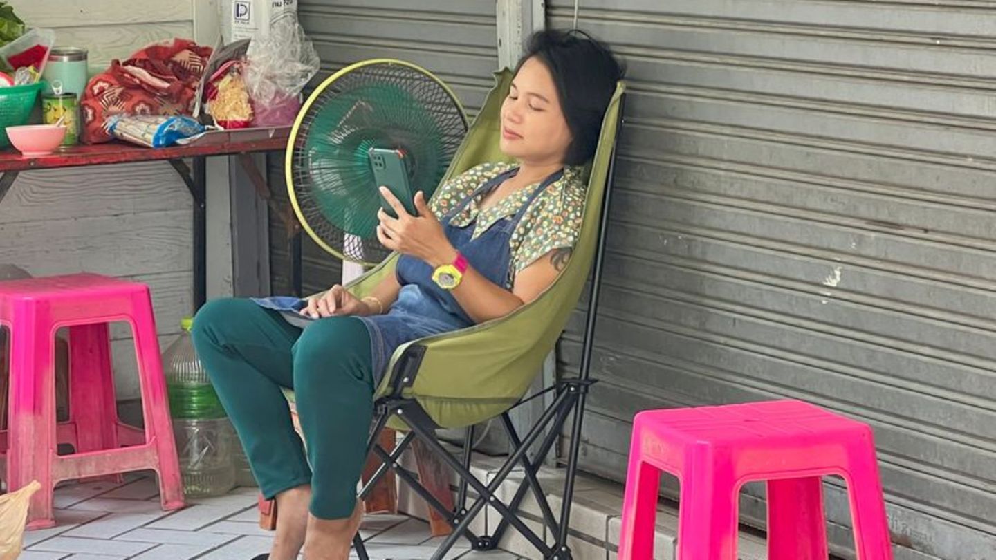 Im Schatten und mit Ventilator: Eine Frau in Bangkok versucht, sich sich abzukühlen. Foto: Carola Frentzen/dpa