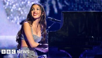 Rodrigo smiles at the crowd as she plays piano on stage