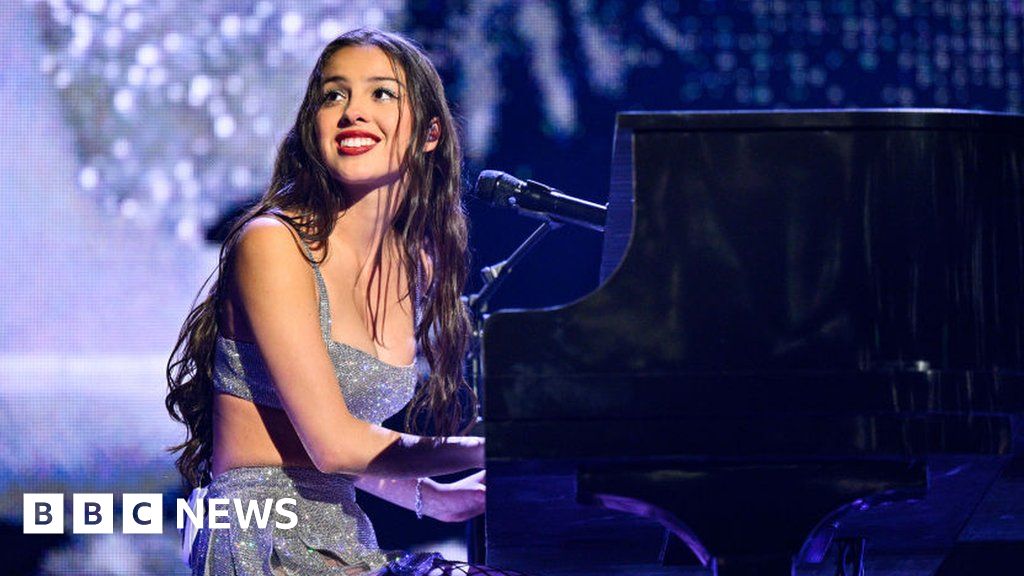 Rodrigo smiles at the crowd as she plays piano on stage