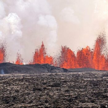 Billowing smoke and flowing lava pouring out of a volcanic fissure