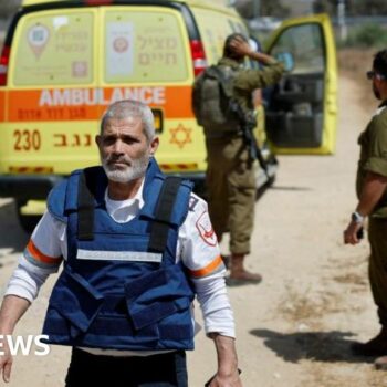 An Israeli medic walks near soldiers and an ambulance after the attack on the Kerem Shalom crossing, near Israel's border with Gaza in southern Israel, 5 May 2024.