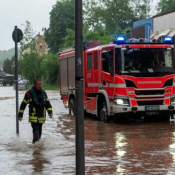 Feuerwehrleute bewegen sich durch das Hochwasser in Saarbrücken. Foto: Harald Tittel/dpa