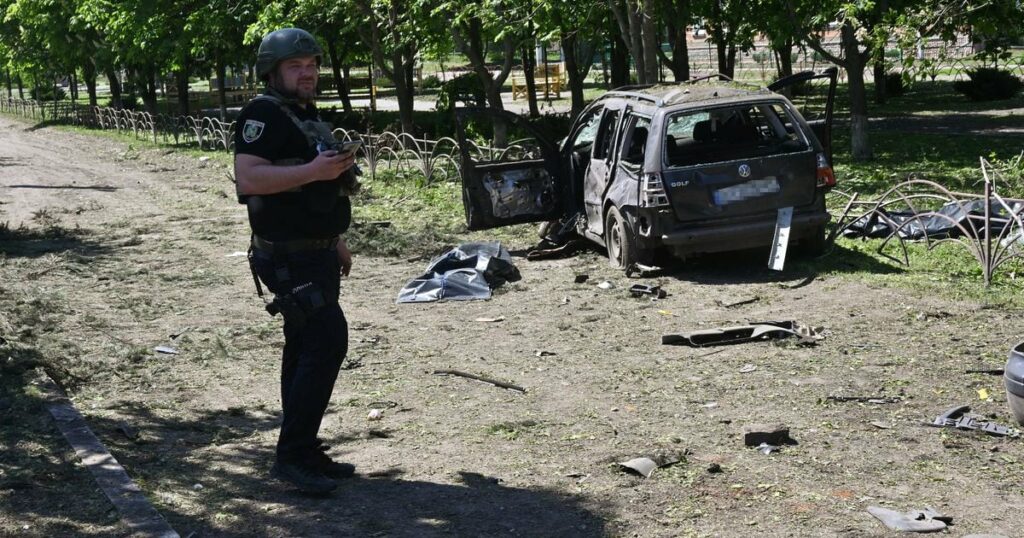 Un policier ukrainien près d'une voiture détruite par une frappe russe à Zlotchiv, dans la région de Kharkiv, le 1er mai 2024