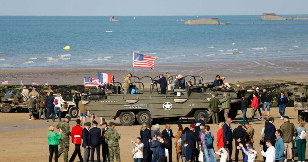 Des visiteurs près de camions amphibies DUKW sur la plage d'Arromanches-les-Bains, le 5 juin 2024, dans le cadre des commémorations du "Jour J " marquant le 80e anniversaire du débarquement allié de la Seconde Guerre mondiale en Normandie