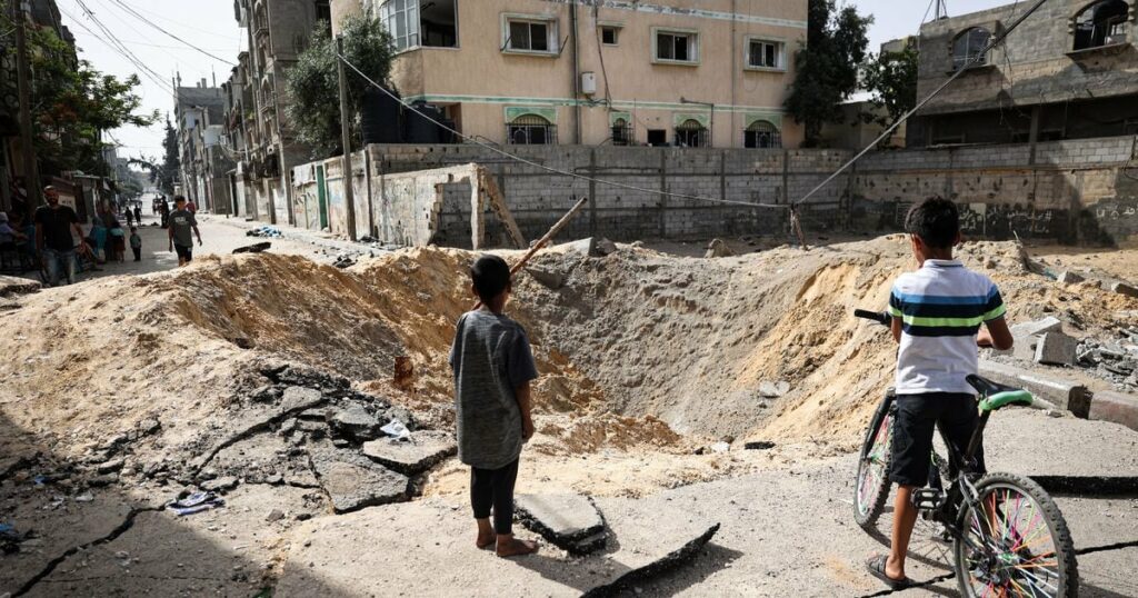 Des enfants devant un cratère causé par un bombardement israélien à Rafah, dans le sud de la bande de Gaza, le 18 mai 2024