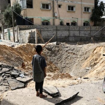 Des enfants devant un cratère causé par un bombardement israélien à Rafah, dans le sud de la bande de Gaza, le 18 mai 2024