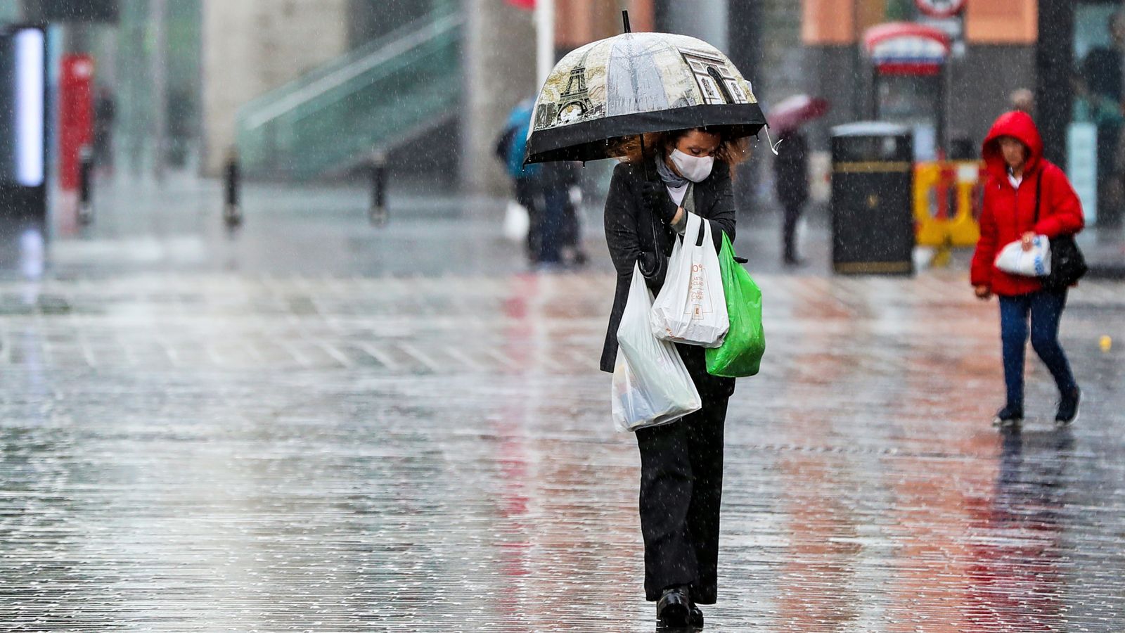 A shopper walks through the rain with an umbrella