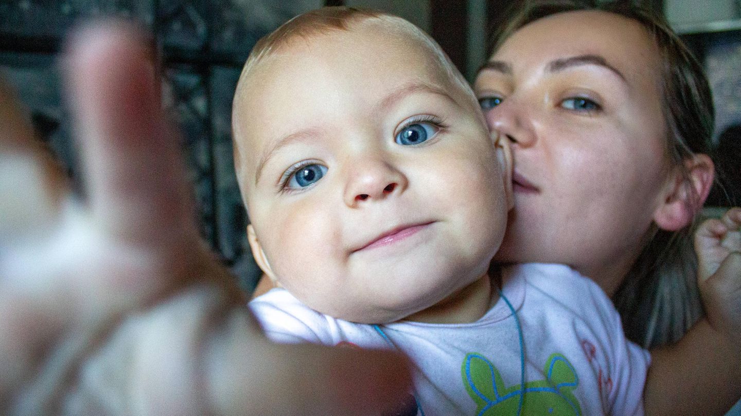 Kinder kriegen: Eine Mutter hält ihr Baby auf dem Arm. Beide schauen in die Kamera