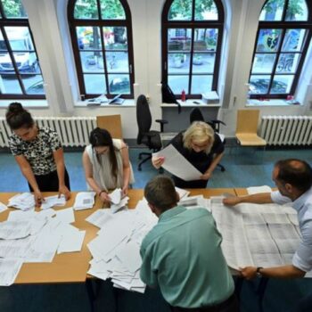 Wahlhelfer sortieren die Stimmzettel der Stichwahl und der Europawahl in einem Wahllokal. Foto: Martin Schutt/dpa