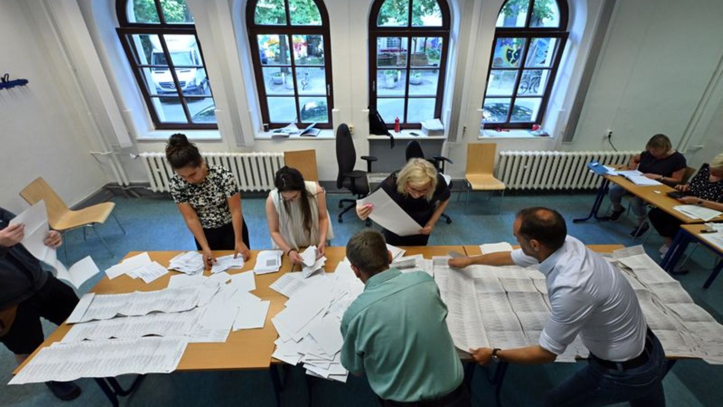 Wahlhelfer sortieren die Stimmzettel der Stichwahl und der Europawahl in einem Wahllokal. Foto: Martin Schutt/dpa