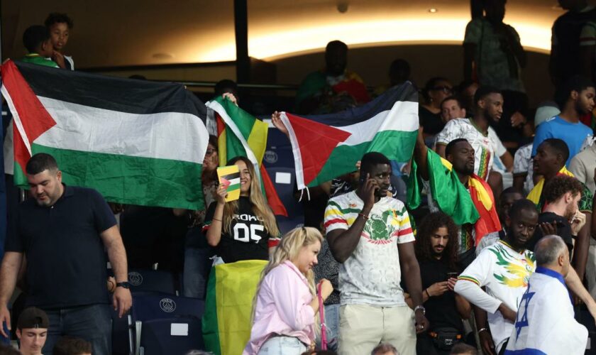 Als die israelische Hymne läuft, präsentieren Zuschauer ihre „Free Palestine“-Shirts
