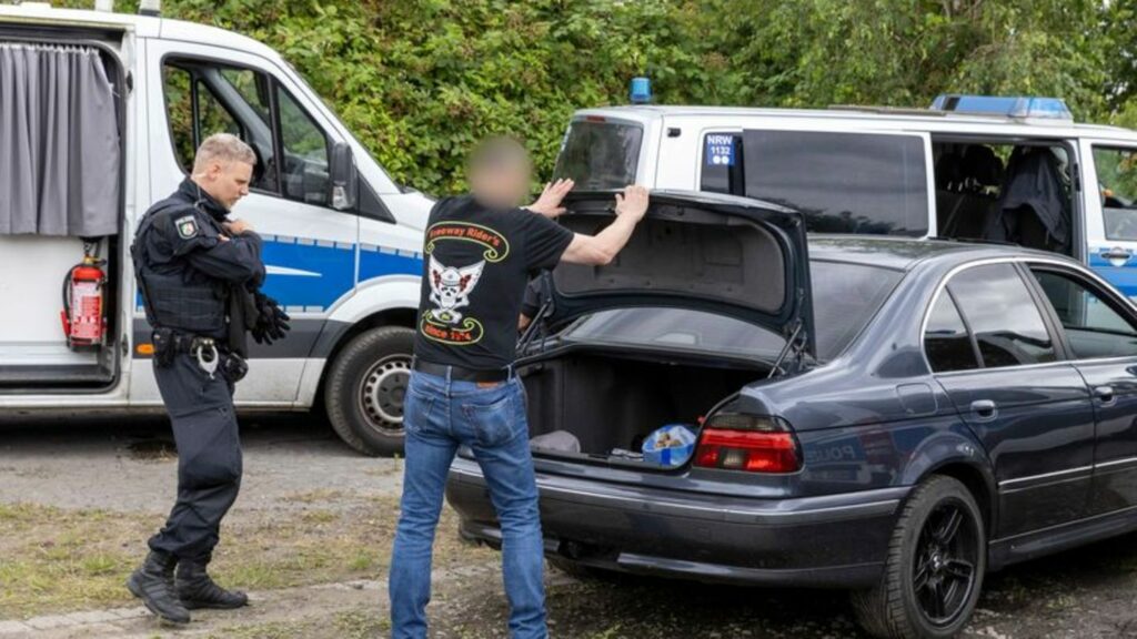 Polizei kontrolliert die Gäste einer Rockerclub-Feier. Ein Mann muss bei der Kontrolle den Kofferraum seines Autos öffnen. Foto: