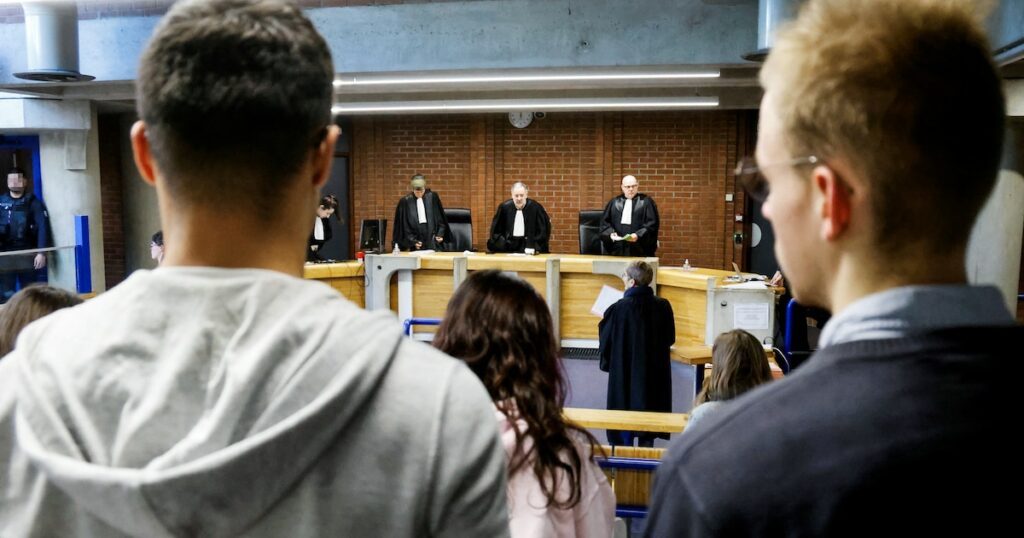 Des membres du public et des avocats se tiennent debout pendant que les juges entrent dans une salle d'audience avant une audience de procès au palais de justice de Bobigny, dans la banlieue nord-est de Paris, le 15 janvier 2024.