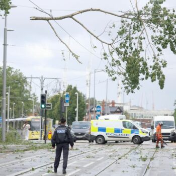 A police officer looks on as workers begin to remove fallen tree branches after strong winds brought by Storm Lilian brought down trees blocking roads and tram routes in Manchester, Britain, August 23, 2024. REUTERS/Phil Noble