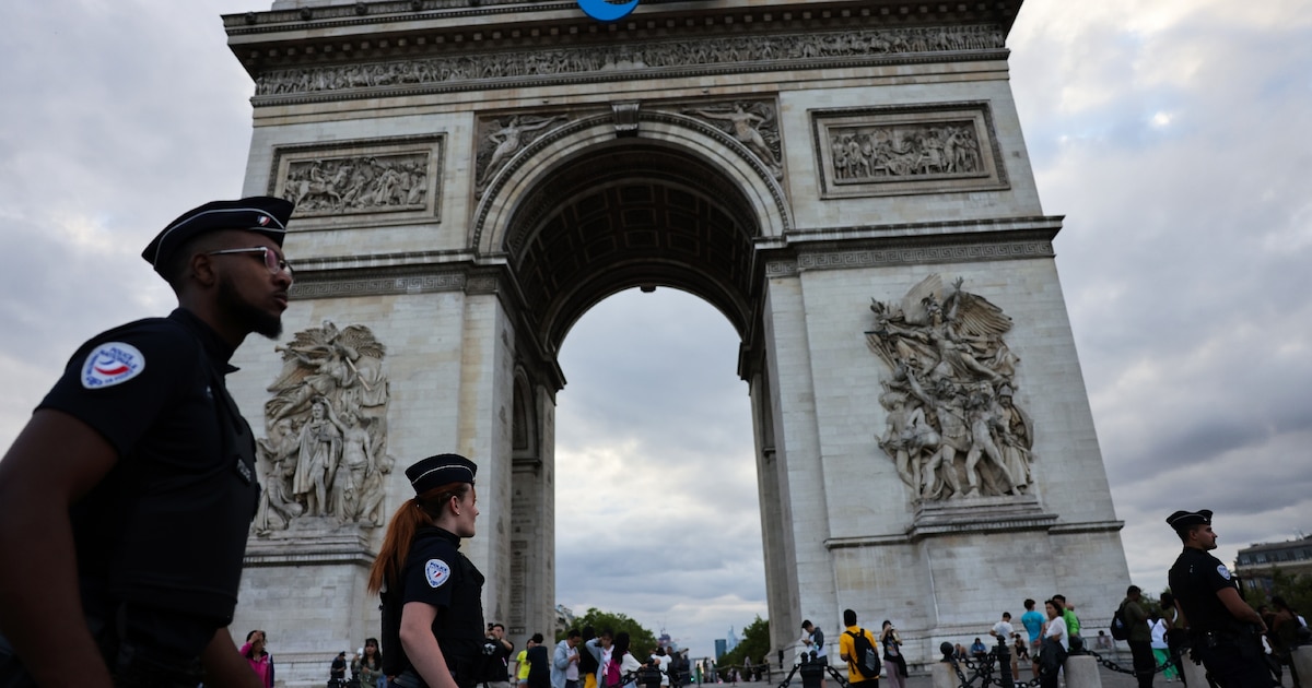 Des policiers passent devant l'Arc de triomphe arborant le sigle des Jeux paralympiques de Paris, le 22 juillet 2024