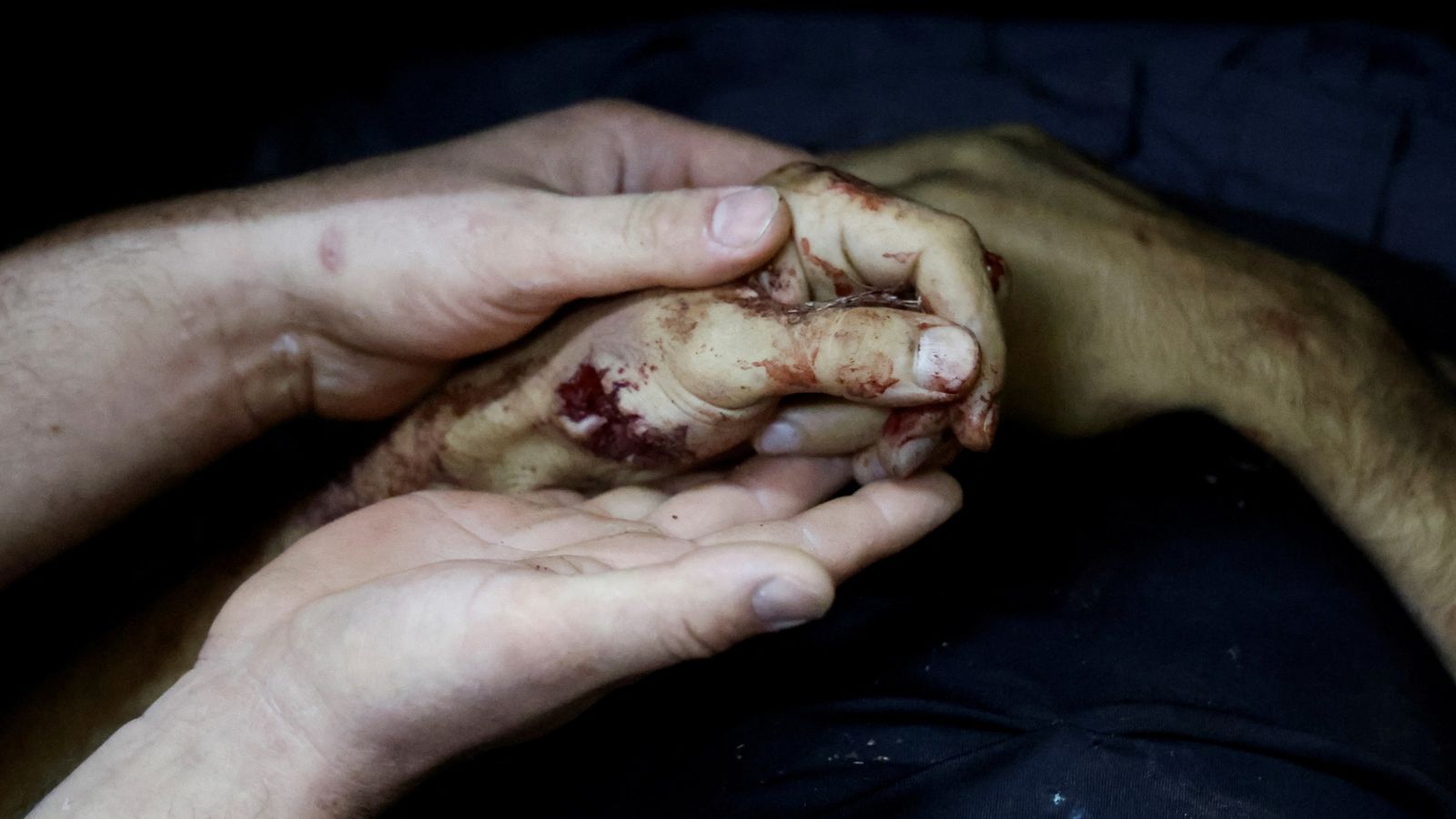 A person holds the hand of a Palestinian killed in an Israeli air strike on a car, at a morgue in Tubas. Pic: Reuters