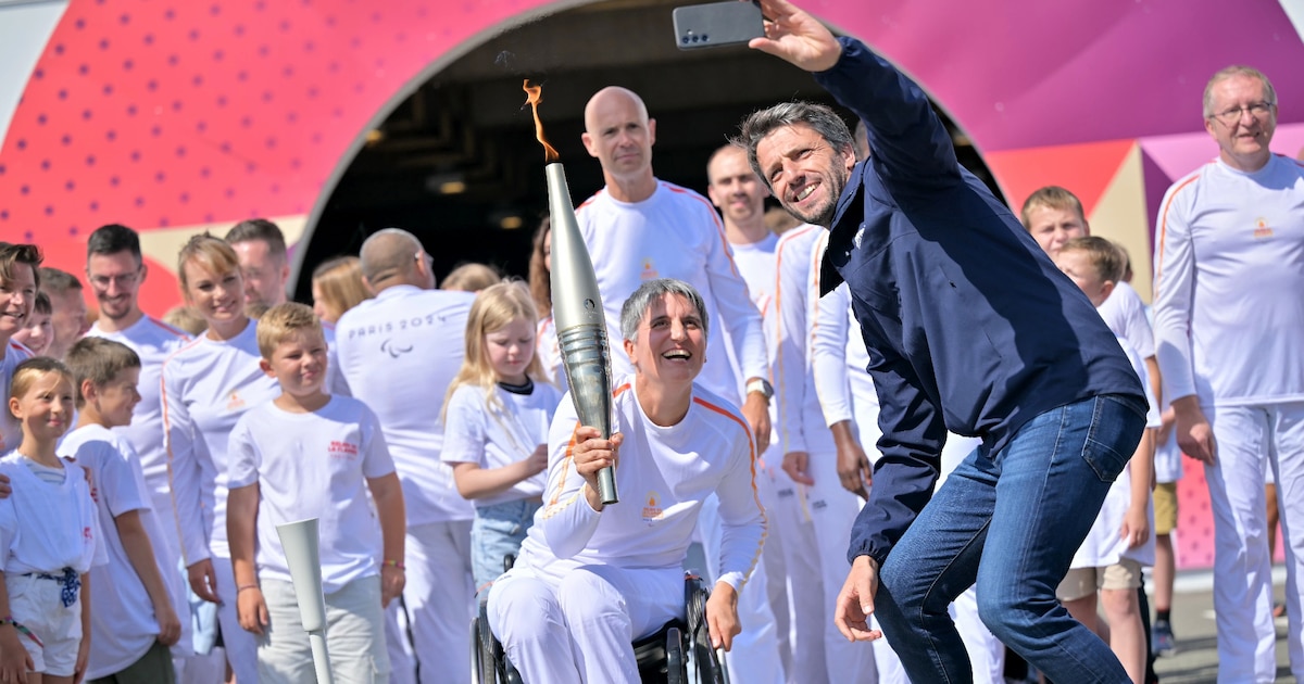 Le président du Comité d'organisation des Jeux (Cojo) Tony Estanguet (D) prend un selfie avec Emmanuelle Assmann porteuse de la flamme paralympique, le 25 août 2024 à Coquelles dans le Pas-de-Calais