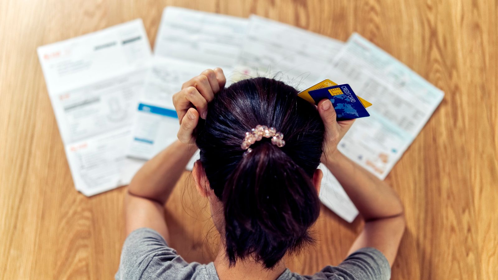 Top view of stressed young sitting Asian woman hands holding the head worry about find money to pay credit card debt and all loan bills. Financial problem concept. (GDA via AP Images)