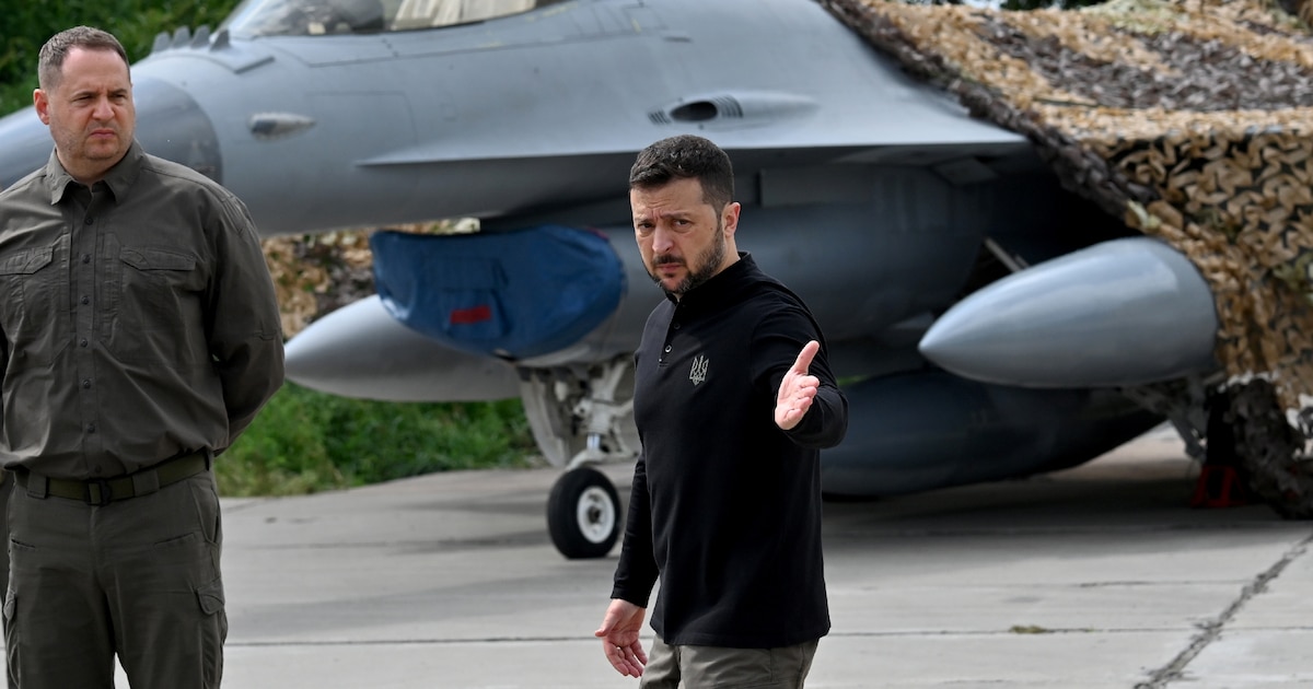 Le président ukrainien Volodymyr Zelensky (D) devant un chasseur F-16 lors d'une cérémonie dans un lieu tenu secret en Ukraine, le 4 août 2024