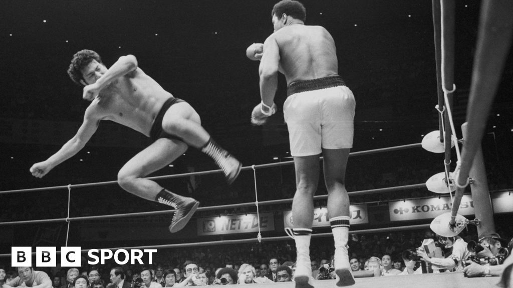 Antonio Inoki is in mid air aiming a kick at Muhammad Ali's legs.