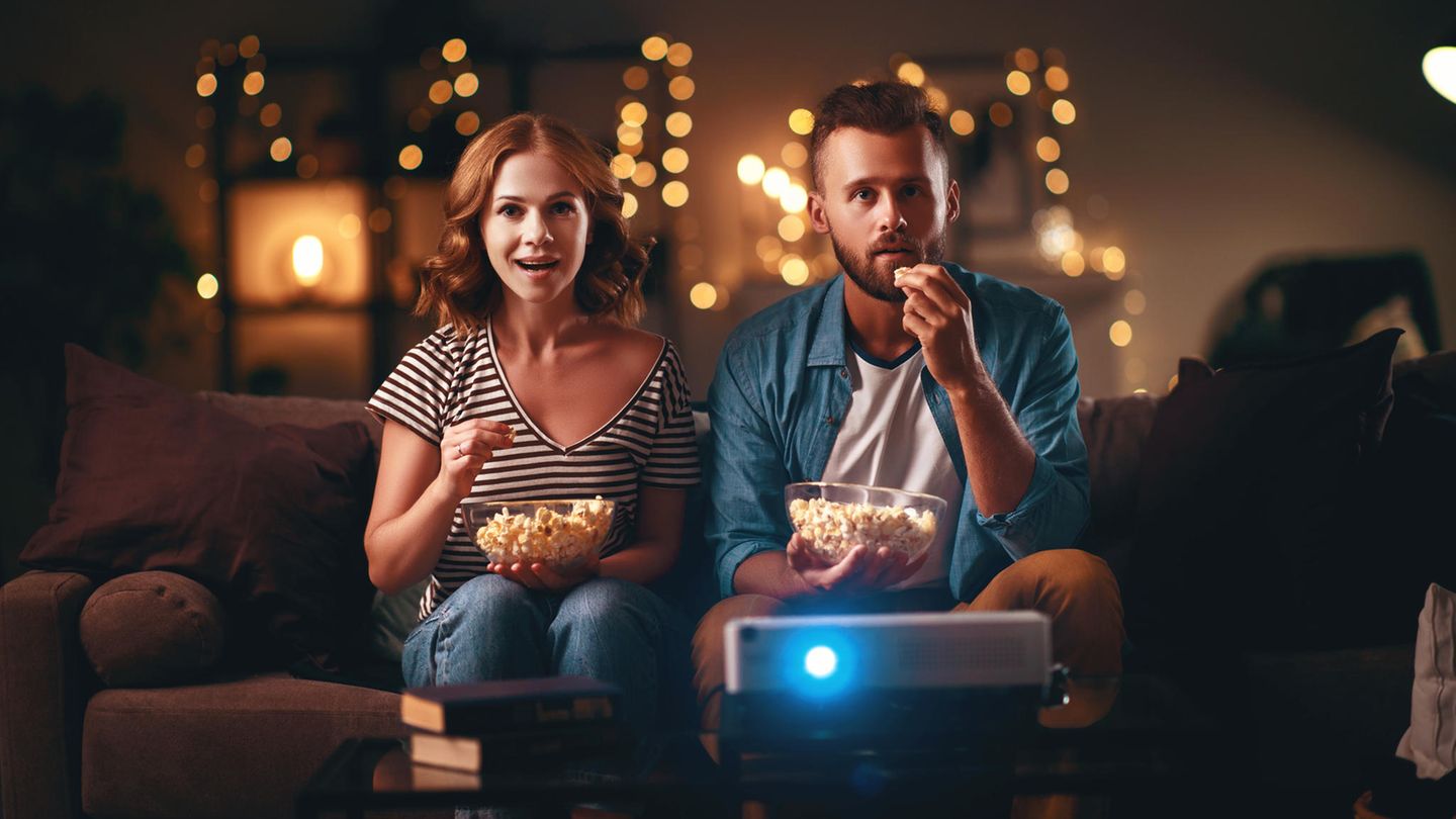 Mann und Frau schauen beim Filmabend auf die Leinwand.