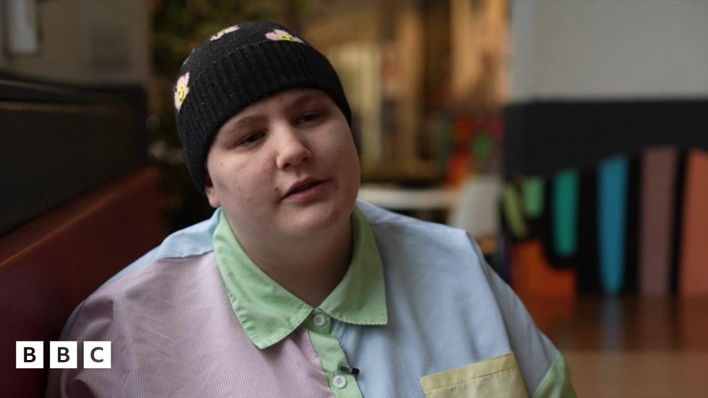 Rhyen smiling at the camera, wearing a black beanie hat and a multicoloured shirt