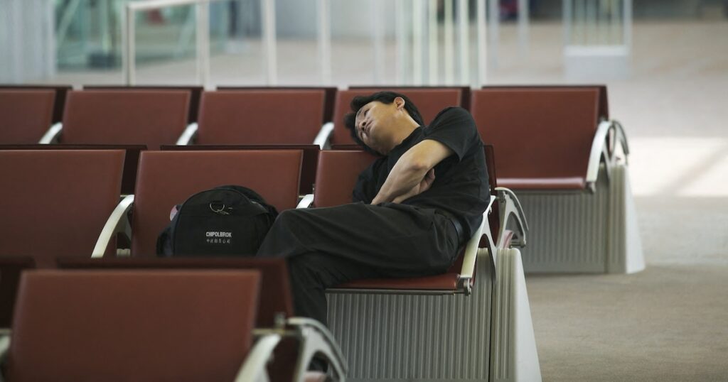 France, Ile-de-France, Seine-et-Marne, Roissy Airport, man sleeping in the waiting lounge. (Photo by Martin/JTP / Photononstop / Photononstop via AFP)