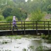 A visitor to Bibury village in Gloucestershire braves the rainy weather. Pic: PA