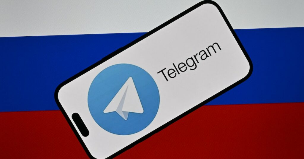 Le logo de la messagerie Telegram devant le drapeau russe.