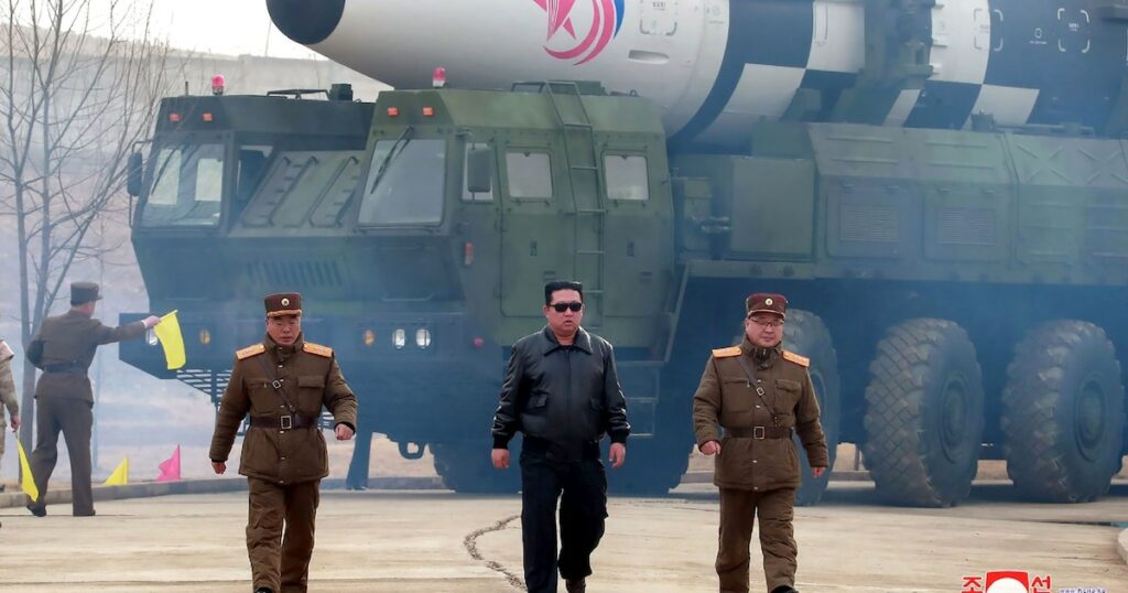 Photo diffusée le 25 mars 2022 par l'agence nord-coréenne Kcna du dirigeant nord-coréen Kim Jong Un (c) devant un missile balistique intercontinental Hwasong-17 dans un lieu non précisé en Corée du Nord, le 24 mars 2022