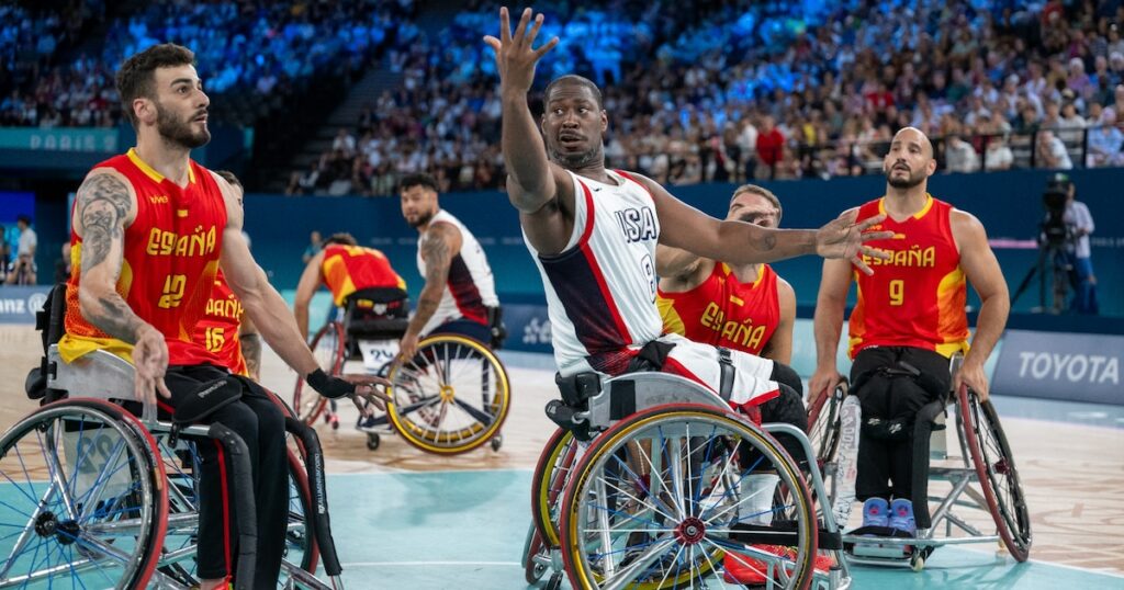 L'Américain Brian Bell (c) passe le ballon sous le regard de L'Espagnol Manuel Lorenzo (g) pendant le tour préliminaire du groupe B du match de basket-ball en fauteuil roulant entre les États-Unis et l'Espagne pendant les Jeux paralympiques de Paris 2024 à Paris, le 29 août 2024