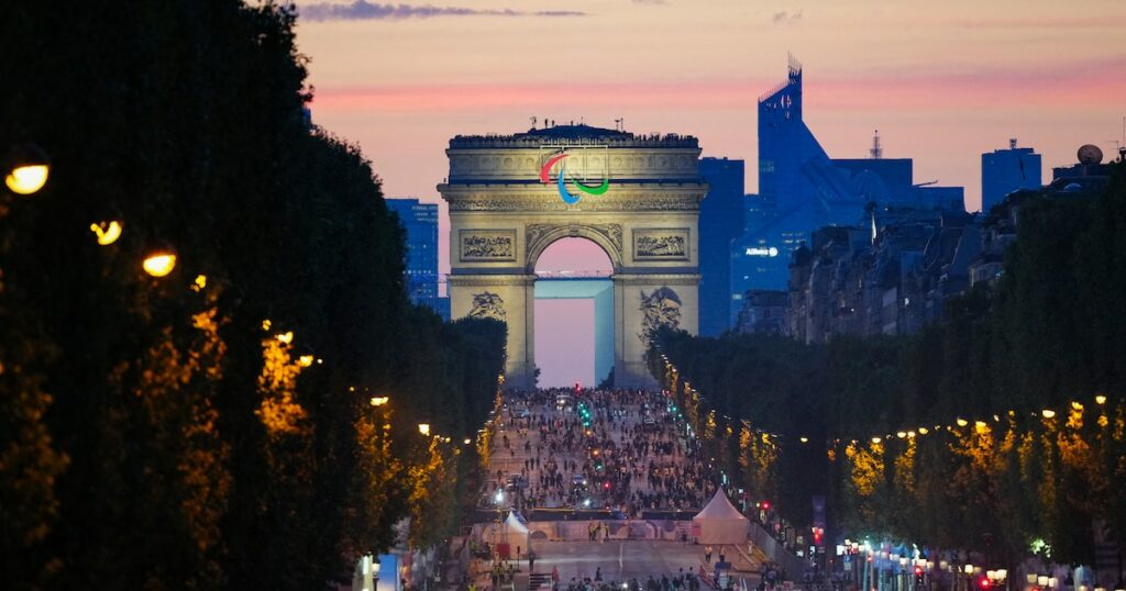 Des athlètes de différentes délégations défilent sur l'avenue des Champs-Elysées avec l'Arc de Triomphe en arrière-plan, lors de la cérémonie d'ouverture des Jeux Paralympiques de Paris 2024, à Paris, le 28 août 2024. (Photo Dimitar DILKOFF / AFP)