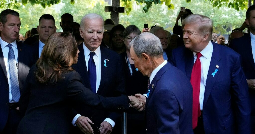 La vice-présidente américaine et candidate démocrate Kamala Harris (de dos) serre la main de l'ancien président républicain Donald Trump, sous les regards du président sortant Joe Biden (de face) et de l'ancien maire de New York Michael Bloomberg (de dos) à la cérémonie du 23e anniversaire des attentats du 11-Septembre 2001, à Manhattan le 11 septembre 2021.