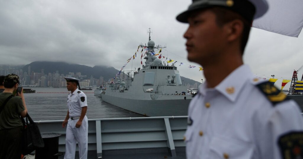 Des marins chinois à bord du Yinchuan, un destroyer de type 052D de la marine de l'Armée populaire de libération (APL), surveillent les visiteurs tandis que le destroyer de type 052C de la marine de l'APL Jinan (C, arrière-plan) est exposé au public à la base navale de Ngong Shuen Chau à Stonecutters.