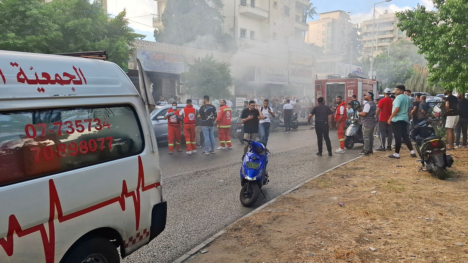 People gather as smoke rises from a mobile shop in Sidon, Lebanon September 18, 2024. REUTERS/Hassan Hankir