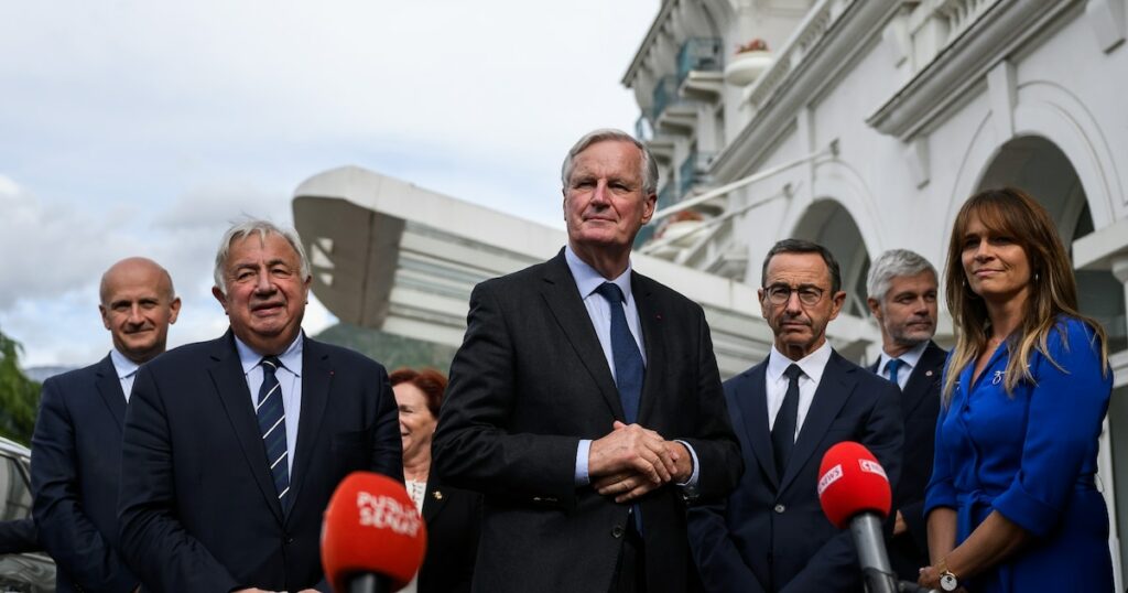 Le Premier ministre français Michel Barnier (C) s'adresse aux journalistes après avoir été accueilli par le chef du groupe parlementaire du parti Les Républicains (LR) au Sénat, à Paris, le 12 septembre 2024