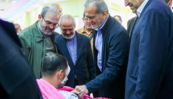 In this photo released by the Iranian Presidency Office, President Masoud Pezeshkian, second right, visits a victim of Lebanon's recent attacks at a hospital in Tehran, Iran, Friday, Sept. 20, 2024. (Iranian Presidency Office via AP)