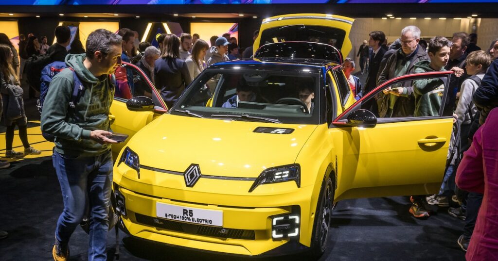 Des visiteurs à côté d'un modèle de voiture électrique Renault R5 E-Tech présenté en première mondiale par le constructeur automobile français lors de la première journée publique du Salon international de l'automobile de Genève, à Genève, le 28 février 2024. (Photo de Fabrice COFFRINI / AFP)