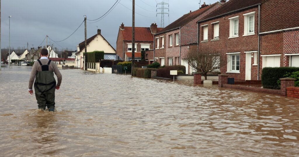 Un homme marche le 3 janvier 2024 dans une rue inondée d'Arques, dans le nord de la France, suite à la crue de l'Aa