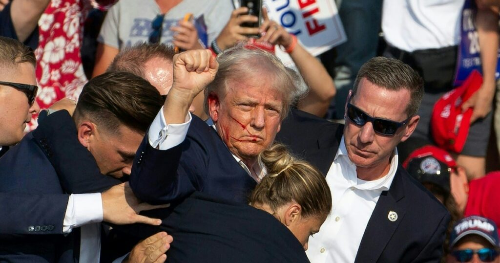 L'ancien président américain Donald Trump, blessé à l'oreille, lève le poing avant d'être évacué de son meeting de campagne à Butler, le 13 juillet 2024 en Pennsylvanie