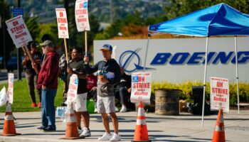 Boeing employees Cham Sin, in black, and Lou Saephanh, right center, wave signs as Boeing workers continue to strike Tuesday, Sept. 24, 2024, near the company's factory in Renton, Wash. (AP Photo/Lindsey Wasson)