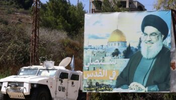 Un véhicule blindé des Nations unies patrouille près d'un panneau publicitaire avec un portrait de Hassan Nasrallah, dans le sud du Liban, le 30 août 2023