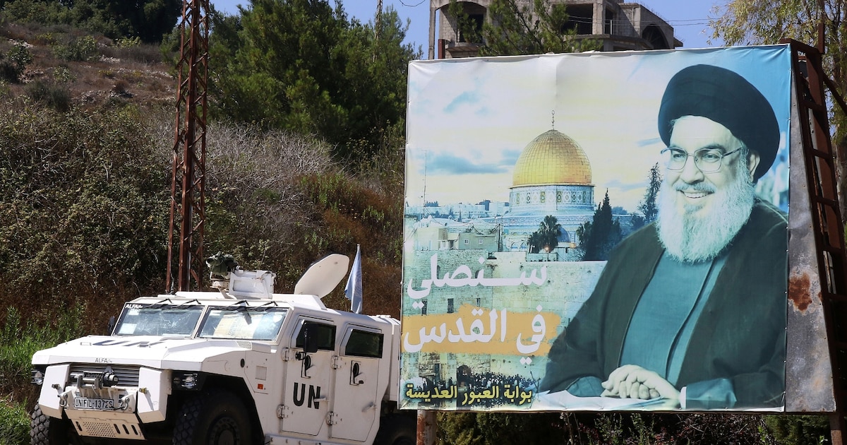 Un véhicule blindé des Nations unies patrouille près d'un panneau publicitaire avec un portrait de Hassan Nasrallah, dans le sud du Liban, le 30 août 2023